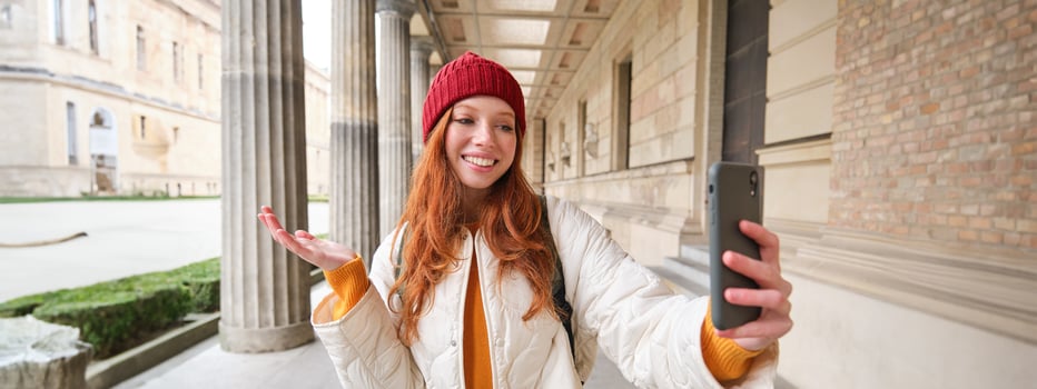 Happy girl tourist demonstrates something on video chat smartphone, shows sightseeing attraction to friend while on mobile phone app call photo