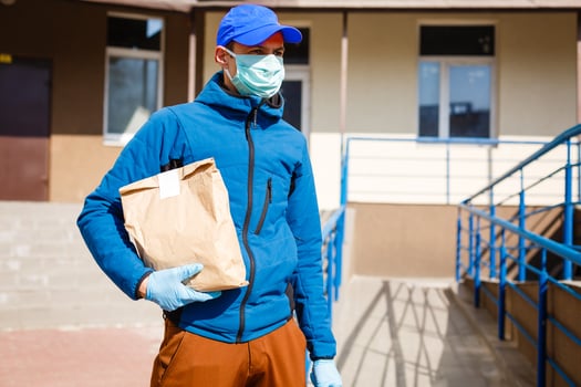 Delivery man holding paper bag with food, food delivery man in protective mask photo