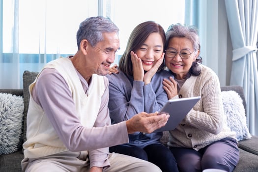 Asian family reunion of senior father, mother and daughter sitting on couch with happy smile in retirement home while looking at the old nostalgic photo in the past