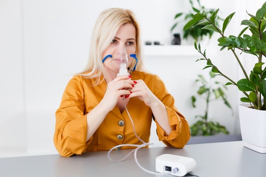 Portrait of adult woman using steam vapor inhaler nebulizer doing aerosol inhalation medicine treatment at home or hospital flu and asthma bronchitis virus healing photo