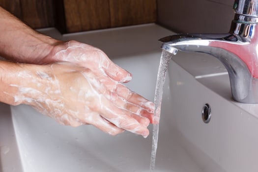 man washes his hands near the white washbasin photo