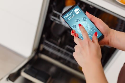 Close-up Of Woman's Hand Showing Dishwasher App On Mobile Phone In Kitchen photo