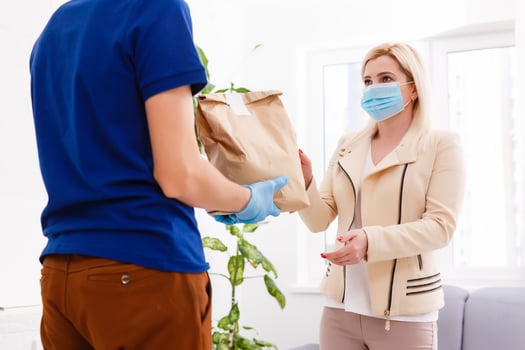 Delivery man holding paper bag with food on white background, food delivery man in protective mask and protective gloves photo