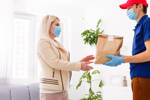 Courier in protective mask and medical gloves delivers takeaway food. Delivery service under quarantine, disease outbreak, coronavirus covid-19 pandemic conditions. photo
