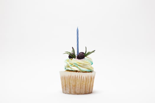 birthday cupcake with one burning candles over white background photo