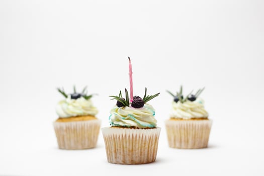birthday three cupcake with one burning candles over white background photo