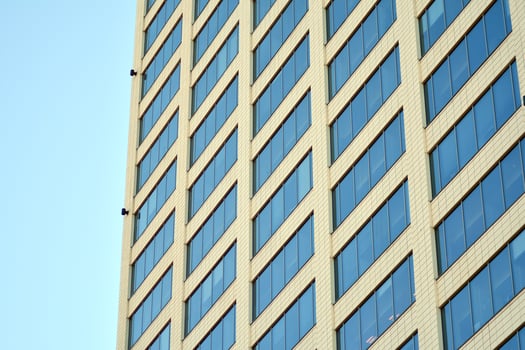 Glass building with transparent facade of the building and blue sky. Structural glass wall reflecting blue sky. Abstract modern architecture fragment. Contemporary architectural background. photo