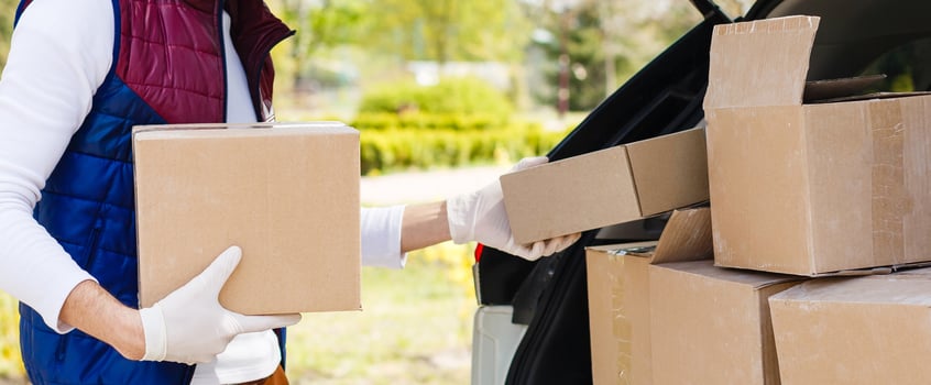Delivery man holding paper bag with food near the car, food delivery man in protective mask photo