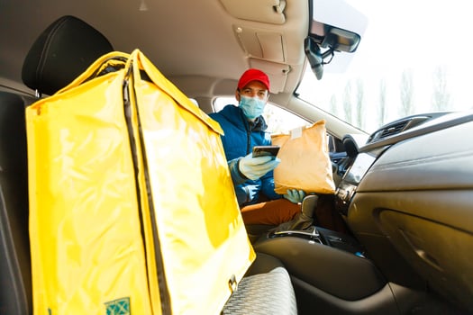 food delivery man in a protective mask and gloves with a thermo backpack near a car during the quarantine period photo