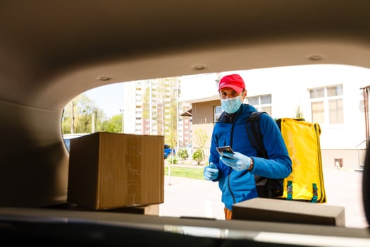 food delivery man in a protective mask and gloves with a thermo backpack near a car during the quarantine period photo