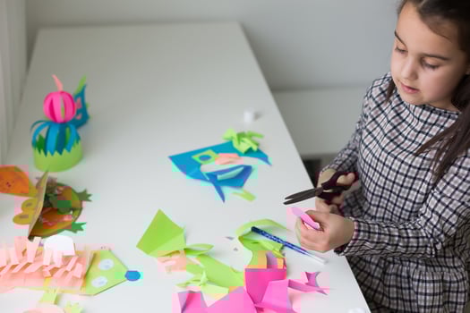 Beautiful little girl cutting paper with scissors on the art lesson class. Children education concept. Kids crafts.Back to schoo photo