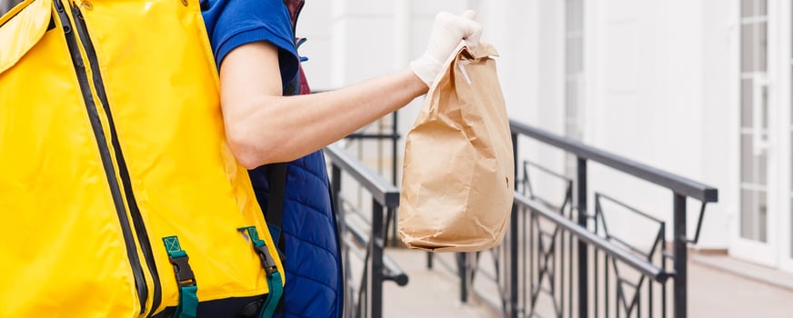 Portrait of a cheerful delivery man standing with yellow thermo backpack for food delivery on the street outdoors photo