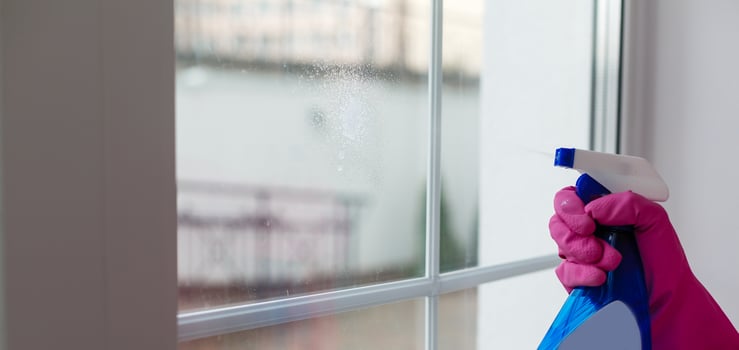 Woman cleaning a window with cleaning sprayer. photo