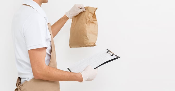 Holding take-out food paper bag. Light grey background, place to insert your text. Delivery man. photo