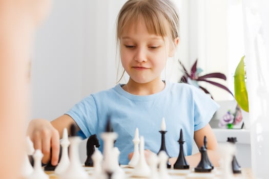 Little girl playing chess at a table photo