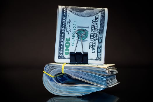 stack of dollar bills collected in an elastic band and a stationery clip photo