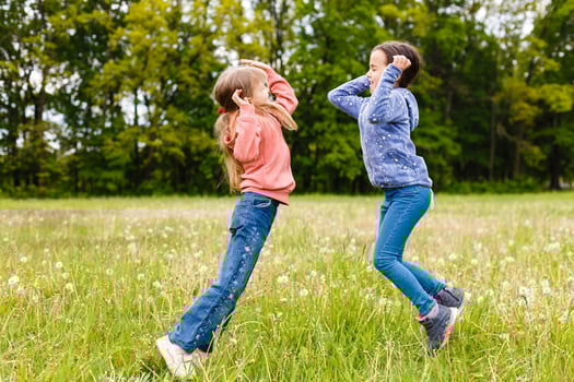 Two sisters hug one another outdoors, happy family photo