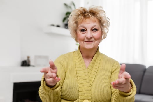 Attractive elderly woman sitting on couch at home, looking at camera, makes video call, communication distantly, modern wireless technologies concept photo