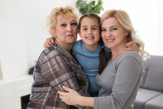 Portrait of three generations of women look at camera posing for family picture, cute little girl hug mom and granny enjoy time at home, smiling mother, daughter and grandmother spend weekend together photo