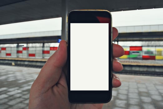 Hand holding smartphone with subway station background photo