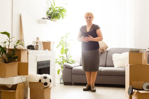 Happy excited mature retired middle aged woman standing in modern living room interior alone with arms outstretched enjoy freedom and wellbeing feel motivated at new furnished renovated home concept photo