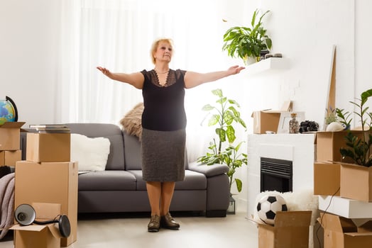 Happy excited mature retired middle aged woman standing in modern living room interior alone with arms outstretched enjoy freedom and wellbeing feel motivated at new furnished renovated home concept photo