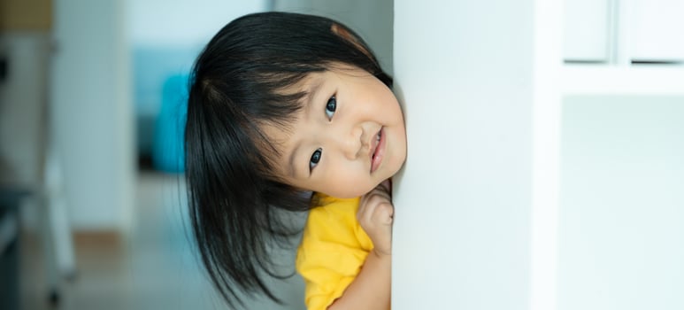 little asian children kid playing hide and seek standing next wall house, Adorable child having fun in the home. happy family have fun with kids, activity, learning, activity, game, meditation photo