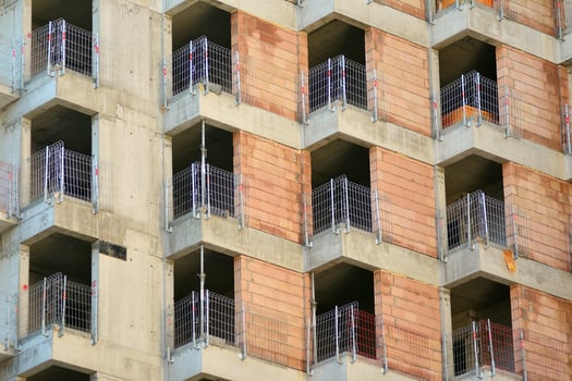 High rise building under construction. Installation of glass facade panels on a reinforced concrete structure. photo