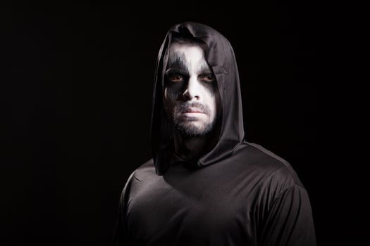 Young man looking serious into the camera dressed up like grim reaper. Halloween costume. photo