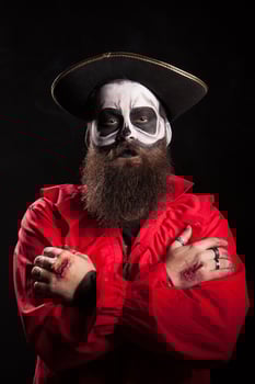 Spooky bearded man with pirate outfit for halloween looking at the camera over black background. photo