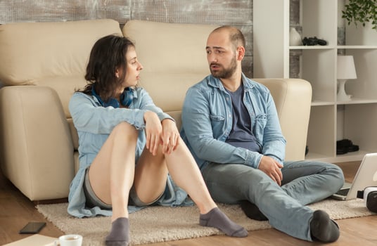 Caucasian young couple having a conversation sitting on carpet. photo