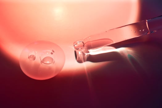 A dropper and a drop of sunscreen body serum in the orange sunset light. photo