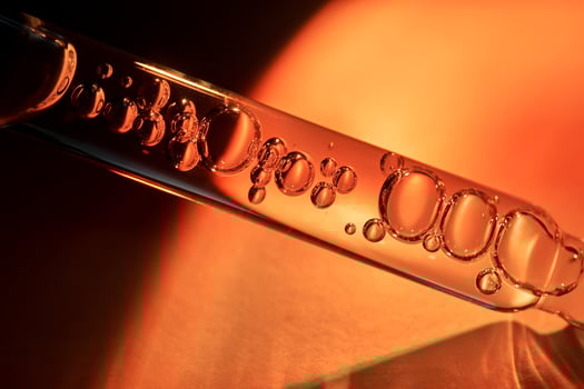 A dropper with sunscreen body serum in the orange sunset light. photo