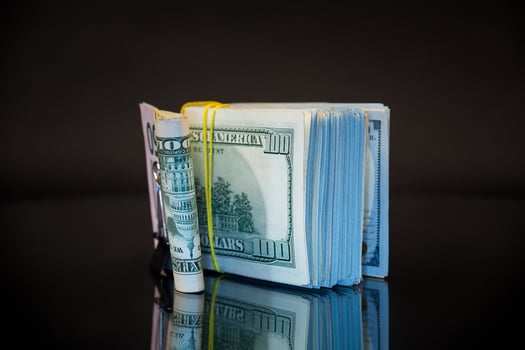 stack of dollar bills collected in an elastic band and a stationery clip photo