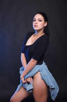 Beautiful young plump woman in black body standing on a white background photo