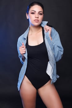 Beautiful young plump woman in black body standing on a white background photo