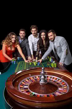 Group of young people behind roulette table in a casino photo