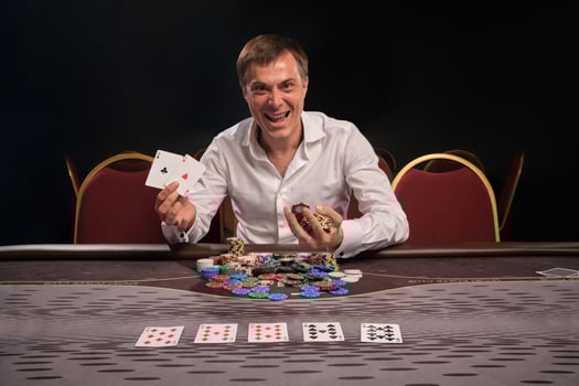 Handsome emotional man is playing poker sitting at the table in casino. photo