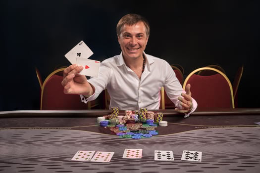Handsome emotional man is playing poker sitting at the table in casino. photo