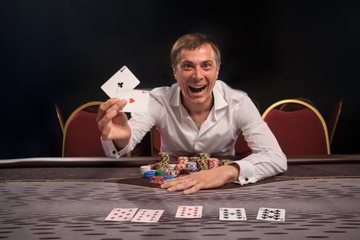 Handsome emotional man is playing poker sitting at the table in casino. photo