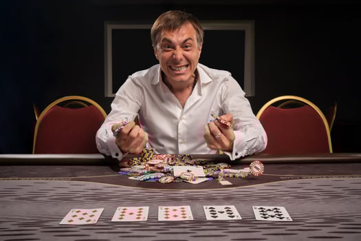Handsome emotional man is playing poker sitting at the table in casino. photo