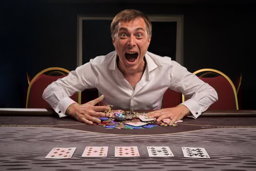 Handsome emotional man is playing poker sitting at the table in casino. photo