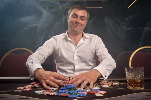 Handsome emotional man is playing poker sitting at the table in casino. photo