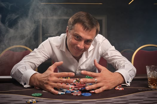 Handsome emotional man is playing poker sitting at the table in casino. photo
