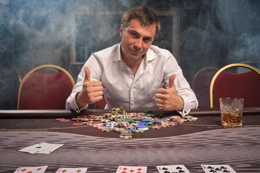 Handsome emotional man is playing poker sitting at the table in casino. photo
