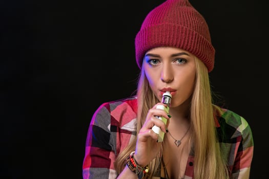 Vaping girl. Young hipster woman vape e-cig on studio on black background. Hip-hop style. Close up. photo