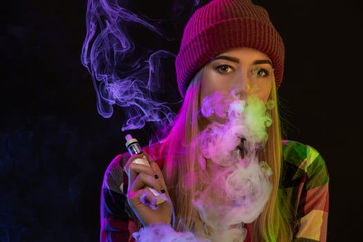 Vaping girl. Young hipster woman vape e-cig on studio on black background. Hip-hop style. Close up. photo