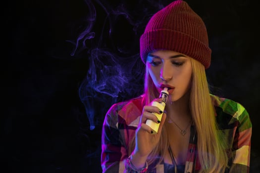 Vaping girl. Young hipster woman vape e-cig on studio on black background. Hip-hop style. Close up. photo