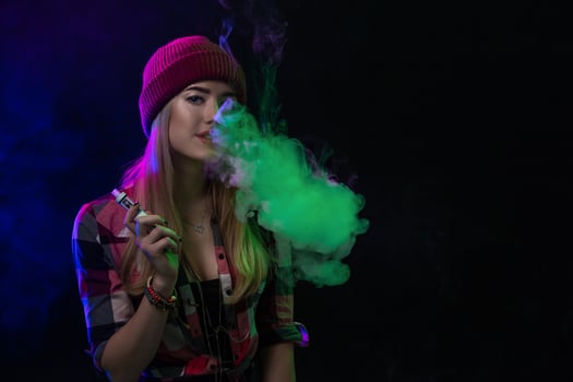 Vaping girl. Young hipster woman vape e-cig on black background. Hip-hop style. Studio shot photo