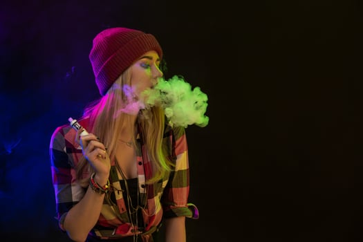 Vaping girl. Young hipster woman vape e-cig on black background. Hip-hop style. Studio shot photo